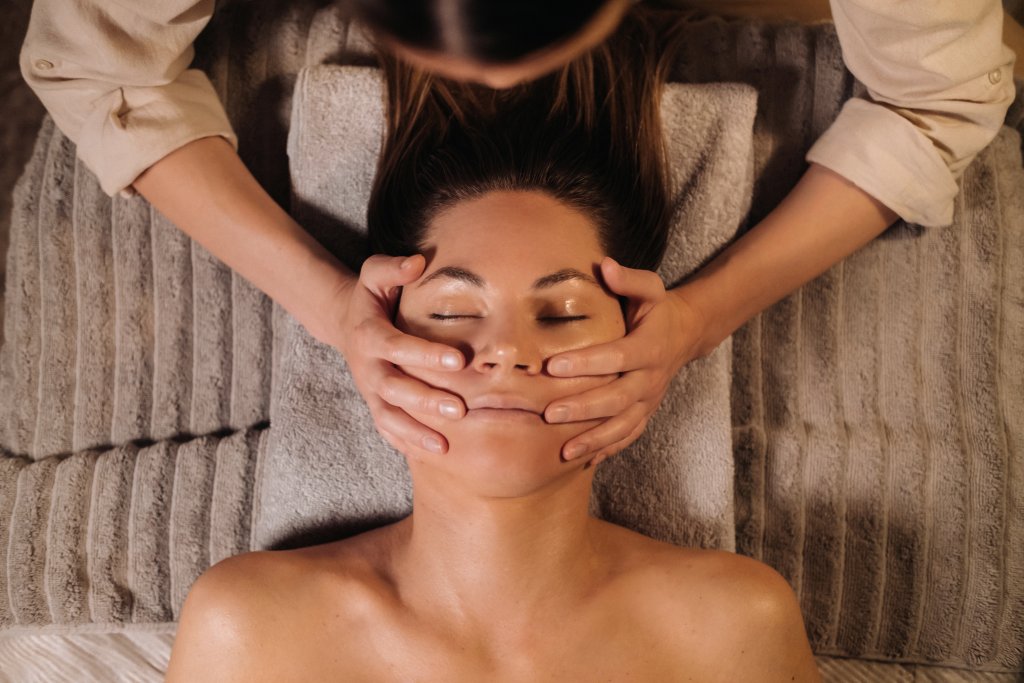 A cosmetologist girl does a facial and neck massage to a girl in the office for skin elasticity