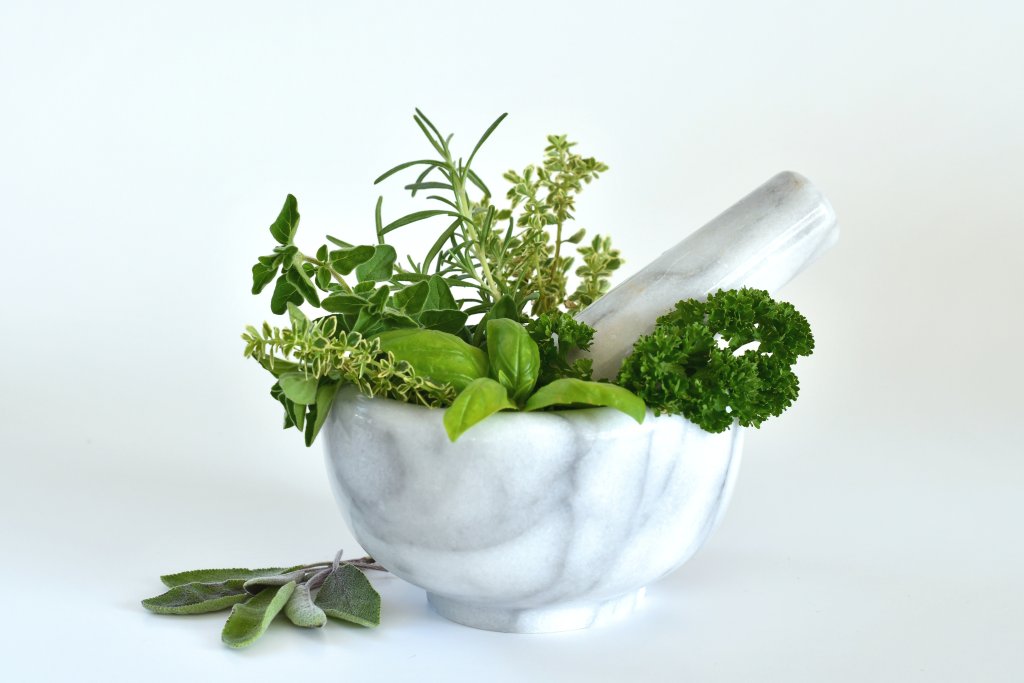 herbal remedies: Fresh green herbs in a white marble mortar and pestle. alternative medicine, herbal remedy