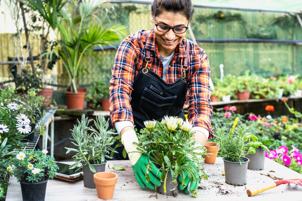 Environmental Impact: Happy Hispanic woman working in plants and flowers garden shop