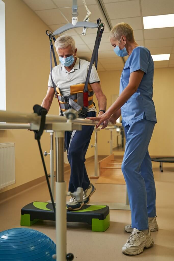 Stroke patient walks between parallel bars at rehabilitation room