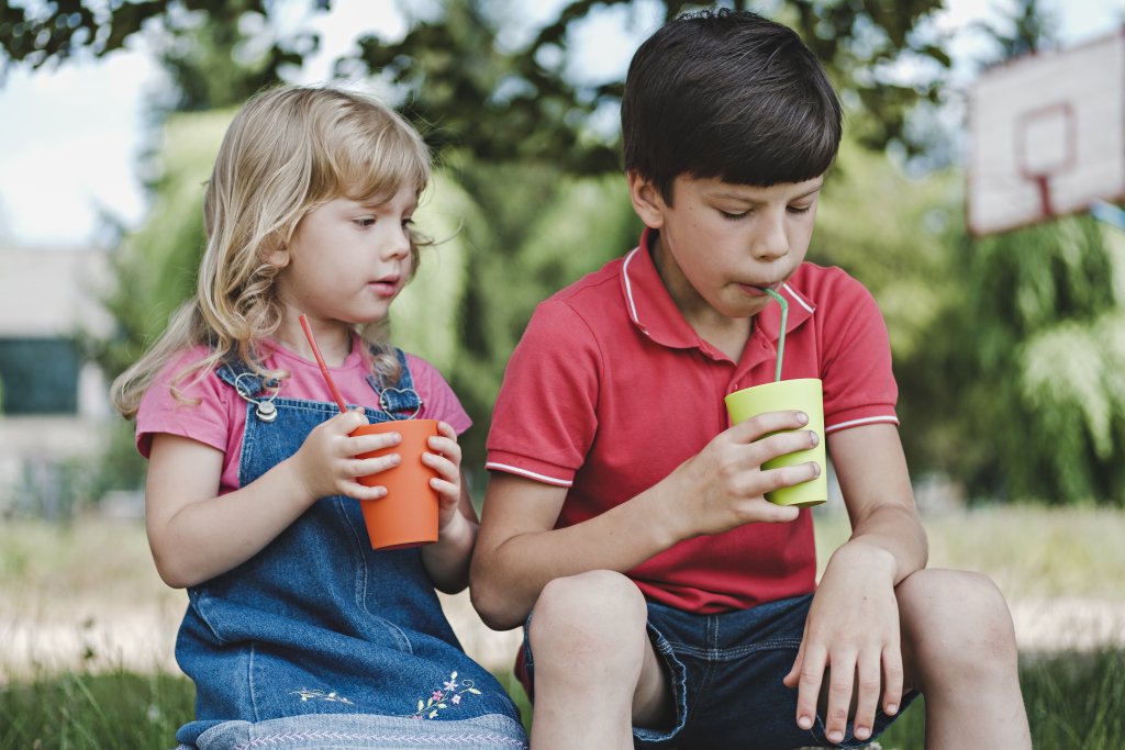 Two young children enjoying a healthy drink