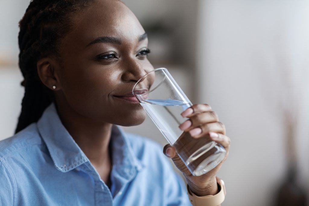Heart-Healthy Foods-Hydration. Beautiful Black Woman Drinking Mineral Water From Glass, Closeup Shot