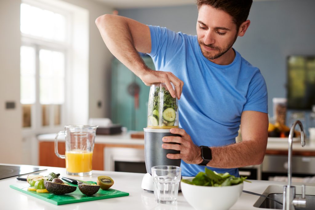 Weight -Man Making Healthy Juice Drink With Fresh Ingredients In Electric Juicer After Exercise
