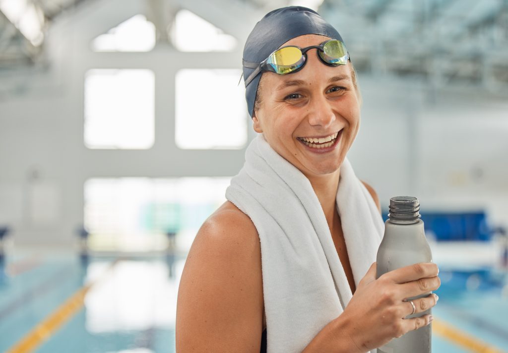 mental health-Portrait, swimming pool and happy woman with bottle for water after workout, training or exercise.