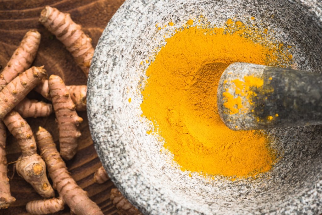 Powerful Foods-Turmeric powder superfood in granite pestle or mortar