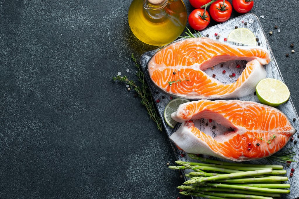 Two raw fresh salmon or trout steaks on ice, rich in omega-3 oil, with lime, thyme and olive oil