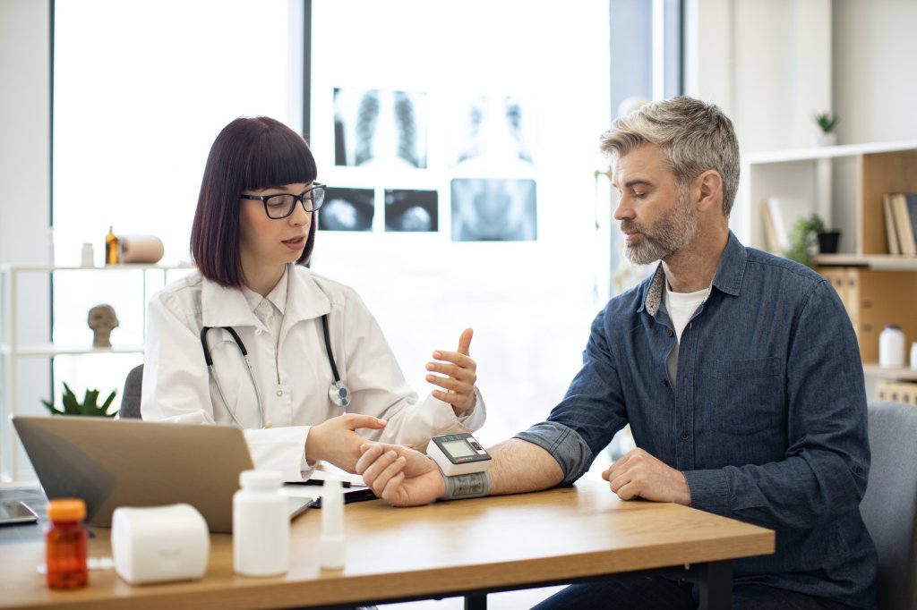 Young cardiologist talking with patient about hypertension