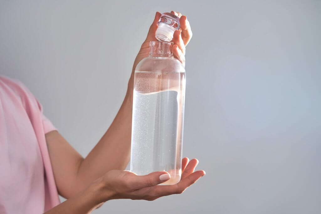 Hydrating Foods-Bottle with drinking water in female hands.