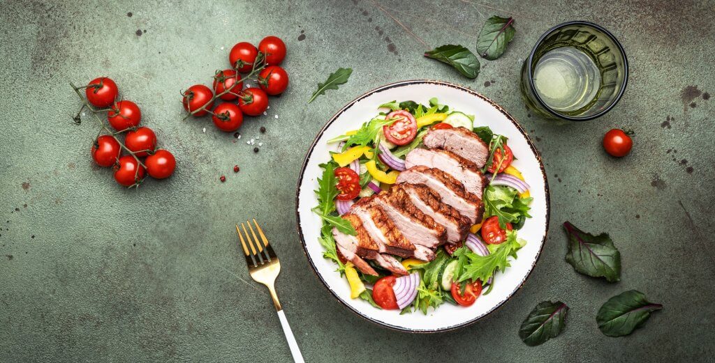 Duck salad with grilled breast and vegetables: red tomato, cucumber, paprika, onion