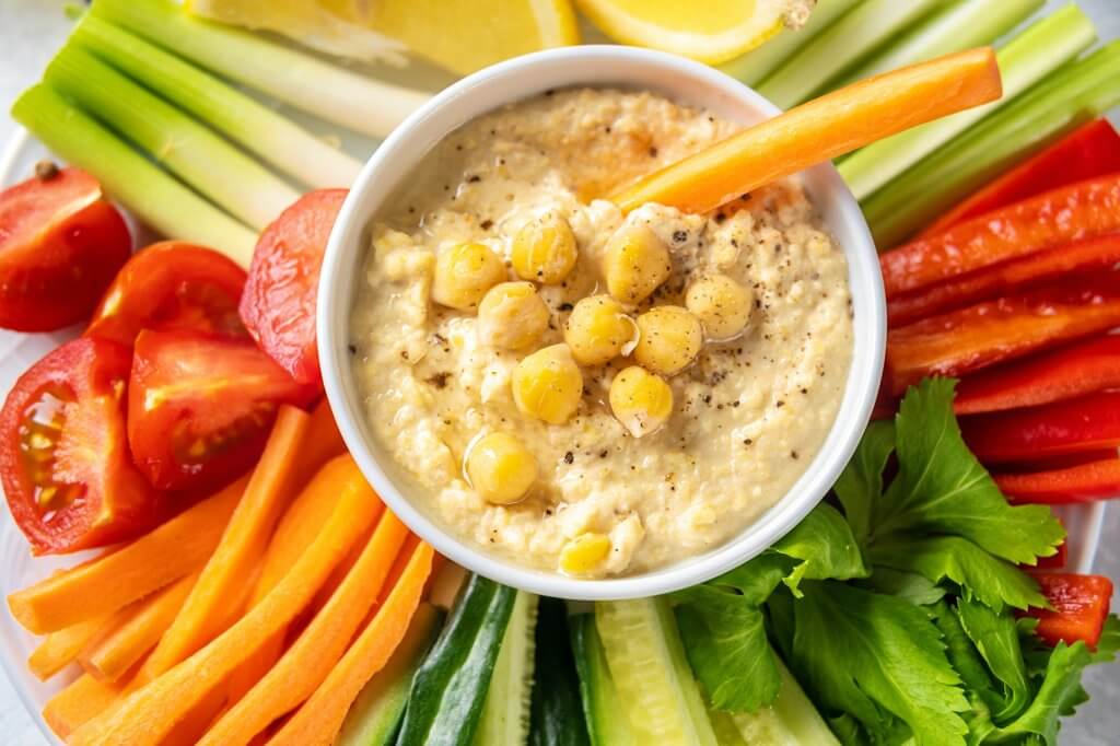 Top view of a hummus plate with vegetable sticks
