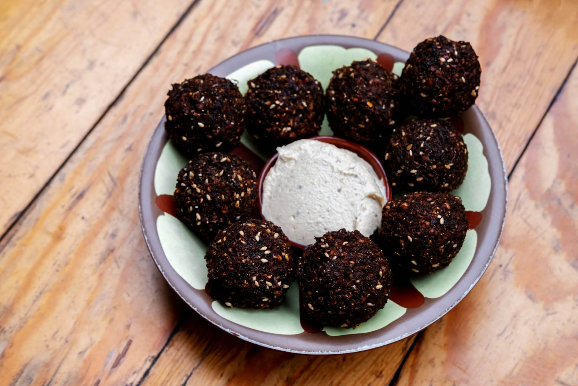 Close up falafel balls with humus on a plate on a wooden background.